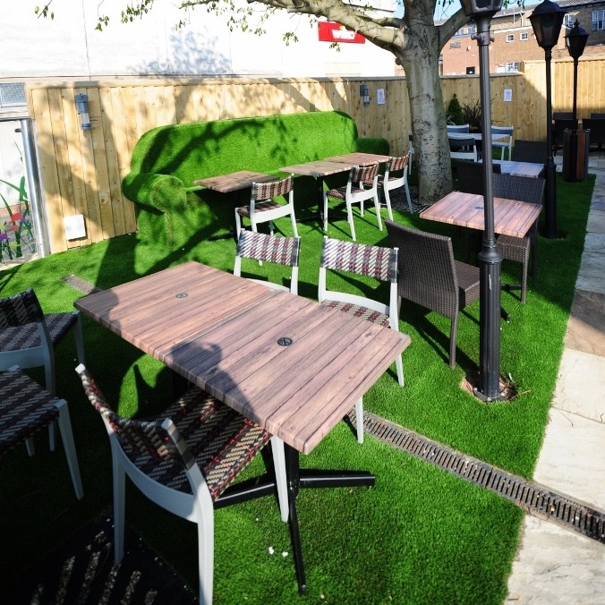 Pub-goers relax on giant grass sofa